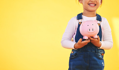 Image showing Girl kid, piggy bank and saving in studio with smile, mockup space and excited by yellow background. Young female child, money box and start investment for promo, financial knowledge or future goal