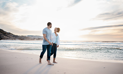 Image showing Couple, holding hands and walking on beach at sunset for Portugal holiday, vacation and travel break by nature ocean mockup. Smile, bonding and love for man and woman on sea sand for romantic sunrise