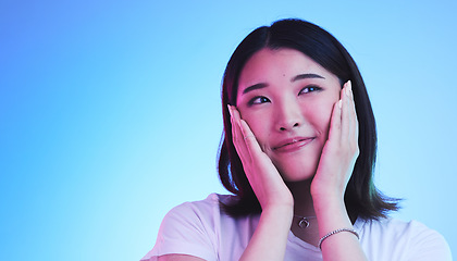 Image showing Face, thinking and Asian woman with beauty or dream with hope or smile isolated in a studio blue background. Cute, shy and happy young female person with skincare or soft skin and with a memory