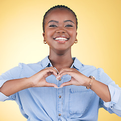 Image showing Happy black woman, portrait and heart hands for love, care or support against a yellow studio background. Face of African female person smile with loving emoji, shape or symbol icon on valentines day