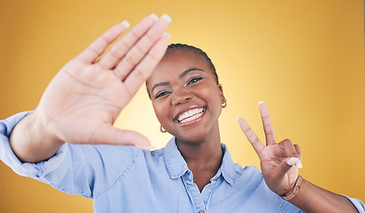 Image showing Selfie, peace sign and smile with portrait of black woman in studio for motivation, social media and influencer. Happy, freedom and profile picture with face of person on yellow background for post