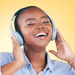 Image showing Singing, music and black woman on headphones, smile and listening in studio isolated on a yellow background. Happy, radio and African person streaming podcast, audio and sound, hearing and freedom.