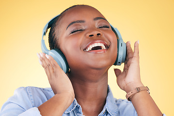 Image showing Singing, music and black woman on headphones, happy and listening in studio isolated on a yellow background. Smile, radio and African person streaming podcast, audio and sound, hearing and freedom.