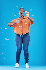 Image showing Excited, happy and black woman on blue background with bubbles for happiness, joy and have fun. Playful, smile and isolated African person in studio with soap bubble for cheerful, magic and aesthetic