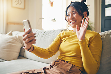 Image showing Phone, wave and Asian woman on video call on sofa, communication and conversation in living room. Smartphone, hello and happy person in webinar, virtual chat and online meeting in house discussion