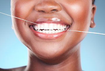 Image showing Happy woman, teeth and dental floss in cleaning, hygiene or cosmetics against a blue studio background. Closeup of female person with big smile flossing in tooth whitening for oral, mouth or gum care