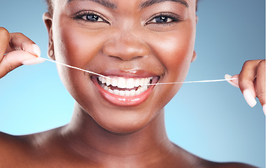 Image showing Happy woman, teeth and dental floss in cleaning, grooming or skincare against a blue studio background. Closeup of female person with big smile flossing in tooth whitening for oral, mouth or gum care