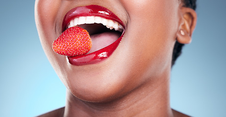Image showing Woman, eating and strawberry, red lipstick and beauty, makeup closeup isolated on blue background. Fruit, healthy and model in a studio with bold cosmetic product, mouth and cosmetology with shine