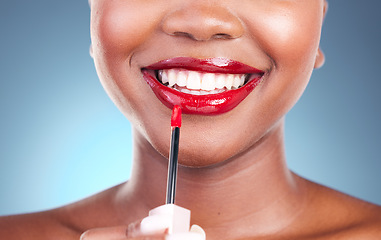 Image showing Woman, smile and red lipstick with brush and beauty, happy with makeup closeup isolated on blue background. Model, bold and cosmetic product on lips, mouth with skin and teeth with shine in studio