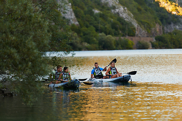 Image showing A group of friends enjoying having fun and kayaking while exploring the calm river, surrounding forest and large natural river canyons