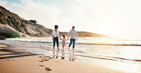 Image showing Bonding, sunset and family on the beach for vacation, adventure or holiday together for bonding. Travel, walking and girl child with her mother and father on the sand by the ocean on a weekend trip.