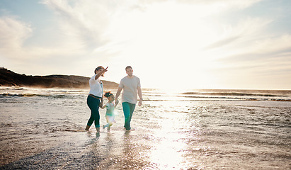 Image showing Beach, sunset and family holding hands together on vacation, adventure or holiday together. Travel, having fun and girl child bonding with mother and father on the sand by the ocean on weekend trip.