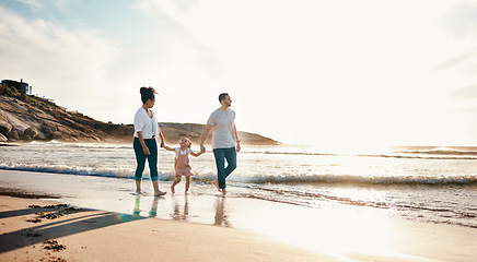 Image showing Walking, holding hands and family on the beach at sunset on vacation, adventure or holiday together. Travel, bonding and girl child with her mother and father on the sand by the ocean on weekend trip