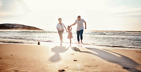 Image showing Beach, sunset and child with her mother and father on a vacation, adventure or holiday together for bonding. Travel, having fun and girl kid walking with parents on the sand by ocean on weekend trip.