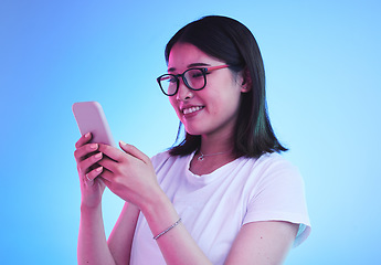 Image showing Phone call, reading an Asian woman in conversation on mobile app to contact person online in studio blue background. Connection, cellphone and young female chatting with smile for communication