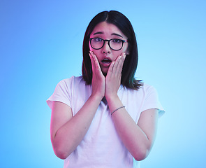 Image showing Surprise, drama and face of Asian woman with fear expression, shocked or open mouth for crisis and fail. Omg, wtf and portrait of person with scared emoji isolated in a studio blue background