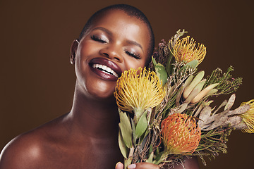 Image showing Aesthetic, beauty and protea with the face of a black woman in studio on brown background for natural treatment. Smile, plant or cosmetics and a young model posing for skincare wellness with flowers