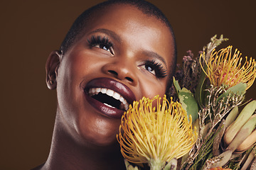 Image showing Beauty, makeup and black woman with flowers in a studio for natural face cosmetics for self care. Happy, smile and young African model with protea floral aesthetic isolated by a brown background.