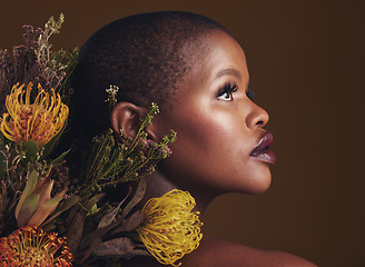 Image showing African woman, flowers and studio profile for beauty, wellness or thinking with vision by brown background. Girl, model and facial makeup for skin, sustainable cosmetics or idea for healthy aesthetic