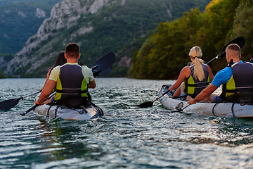 Image showing A group of friends enjoying having fun and kayaking while exploring the calm river, surrounding forest and large natural river canyons