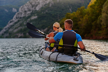 Image showing A group of friends enjoying having fun and kayaking while exploring the calm river, surrounding forest and large natural river canyons