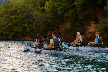 Image showing A group of friends enjoying having fun and kayaking while exploring the calm river, surrounding forest and large natural river canyons