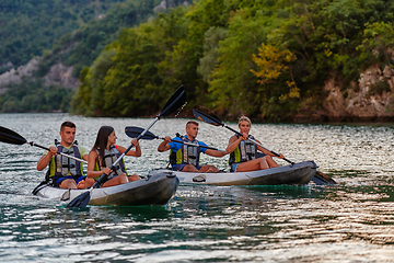 Image showing A group of friends enjoying having fun and kayaking while exploring the calm river, surrounding forest and large natural river canyons