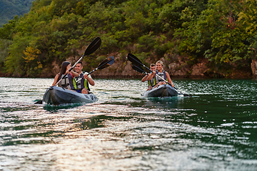 Image showing A group of friends enjoying having fun and kayaking while exploring the calm river, surrounding forest and large natural river canyons