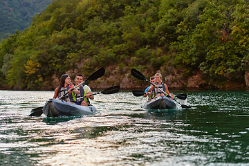 Image showing A group of friends enjoying having fun and kayaking while exploring the calm river, surrounding forest and large natural river canyons