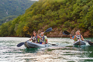 Image showing A group of friends enjoying having fun and kayaking while exploring the calm river, surrounding forest and large natural river canyons