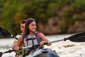 Image showing A young couple enjoying an idyllic kayak ride in the middle of a beautiful river surrounded by forest greenery