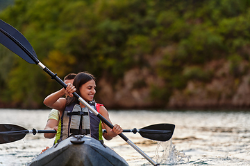 Image showing A young couple enjoying an idyllic kayak ride in the middle of a beautiful river surrounded by forest greenery