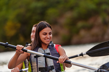 Image showing A young couple enjoying an idyllic kayak ride in the middle of a beautiful river surrounded by forest greenery