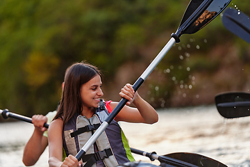 Image showing A young couple enjoying an idyllic kayak ride in the middle of a beautiful river surrounded by forest greenery