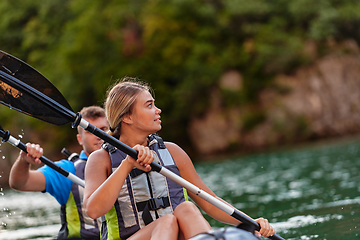 Image showing A young couple enjoying an idyllic kayak ride in the middle of a beautiful river surrounded by forest greenery