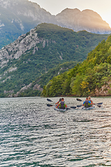 Image showing A group of friends enjoying having fun and kayaking while exploring the calm river, surrounding forest and large natural river canyons