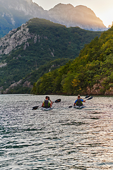 Image showing A group of friends enjoying having fun and kayaking while exploring the calm river, surrounding forest and large natural river canyons