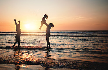 Image showing Silhouette, sunset and dad lifting child in air at beach with lgbt family and waves in the ocean with fun and support on adventure. Gay parents, kid and father play with girl in the sea with love