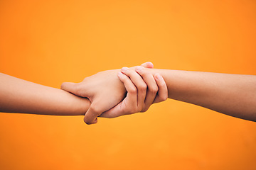 Image showing Holding hands, studio and closeup for support, help and care for teamwork by orange background. People, friends and together for solidarity, link and connection with synergy, partnership and strong