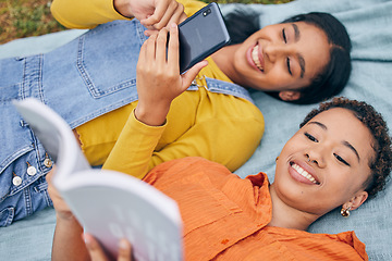 Image showing Girl friends, park and top view with reading, book and smartphone for blog, relax or knowledge in nature. Gen z students, phone and story on blanket, picnic or outdoor for holiday, backyard or garden