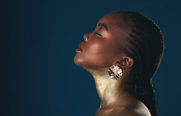 Image showing Profile, beauty and black woman in gold for culture, heritage or tradition on a blue background in studio. Face, mockup and african style with a young model closeup for elegance or cosmetics