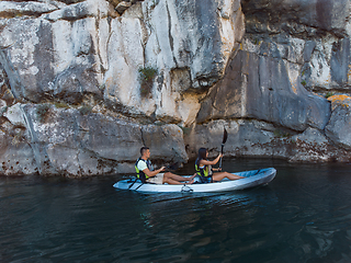 Image showing A young couple enjoying an idyllic kayak ride in the middle of a beautiful river surrounded by forest greenery