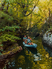 Image showing A young couple enjoying an idyllic kayak ride in the middle of a beautiful river surrounded by forest greenery