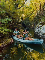 Image showing A young couple enjoying an idyllic kayak ride in the middle of a beautiful river surrounded by forest greenery