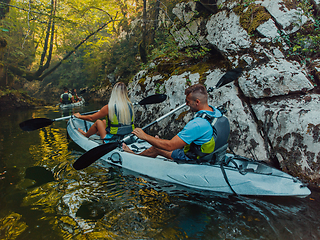 Image showing A young couple enjoying an idyllic kayak ride in the middle of a beautiful river surrounded by forest greenery