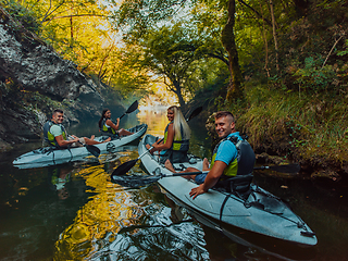 Image showing A group of friends enjoying having fun and kayaking while exploring the calm river, surrounding forest and large natural river canyons