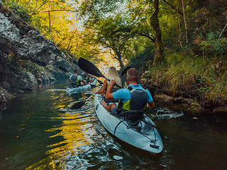 Image showing A group of friends enjoying having fun and kayaking while exploring the calm river, surrounding forest and large natural river canyons