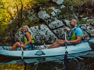 Image showing A young couple enjoying an idyllic kayak ride in the middle of a beautiful river surrounded by forest greenery