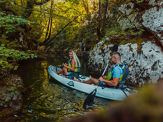 Image showing A young couple enjoying an idyllic kayak ride in the middle of a beautiful river surrounded by forest greenery