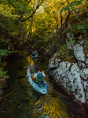 Image showing A young couple enjoying an idyllic kayak ride in the middle of a beautiful river surrounded by forest greenery